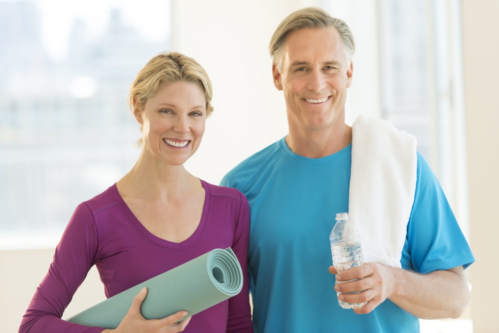 happy mature couple with exercise mat