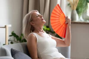 senior woman using waving fan suffer from overheating