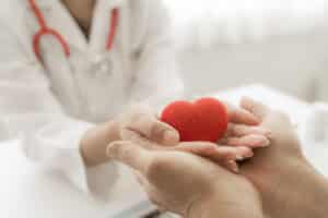 Image of doctor and patient holding a heart shape in their hands together to signify heart health