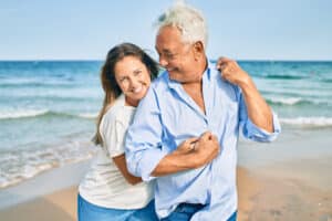 Cute mature couple hugging and laughing on the beach romantically