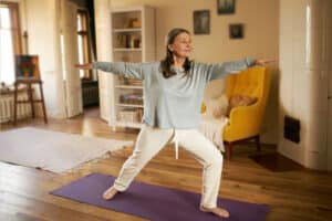 Healthy older woman doing yoga to destress after summer