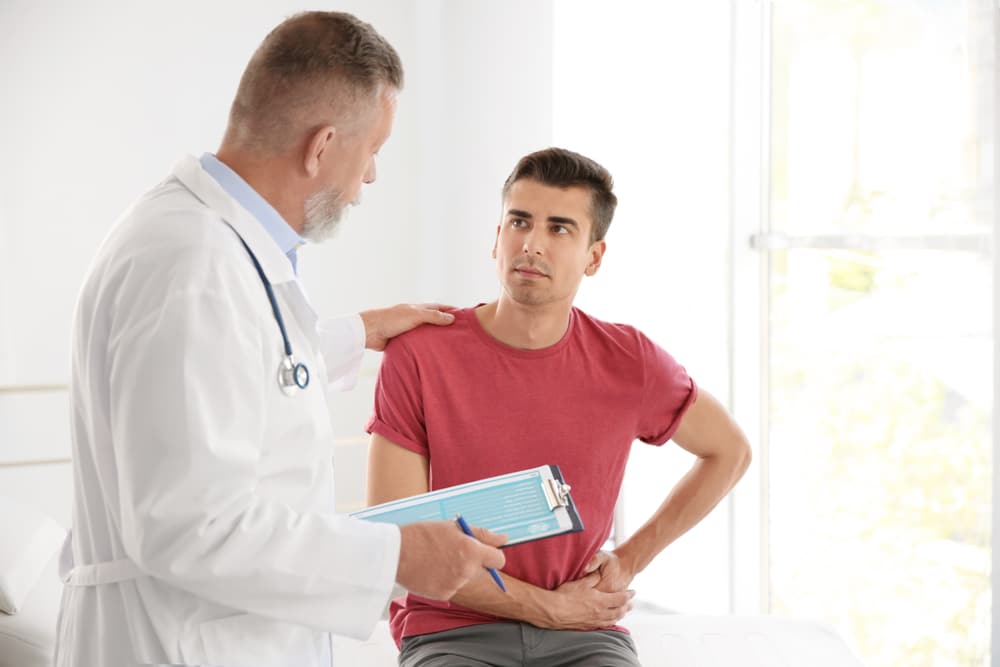 Doctor supporting a male patient experiencing fatigue and emotional stress related to low testosterone symptoms.